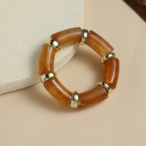 Detailed close-up of amber resin segments and gold metal links on a curved bangle