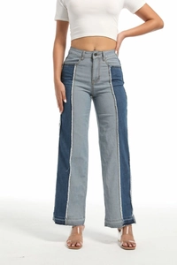 Macro detail of high-waisted patchwork jeans showing frayed edges and dual-tone denim texture