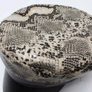 Detailed view of faux snakeskin leather texture and black brim of this flat top army cap