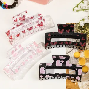 Set of four large acrylic hair claws with red and pink heart patterns in black and clear