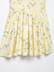 Close-up detail of pale yellow poplin mini dress with floral print and pleated texture