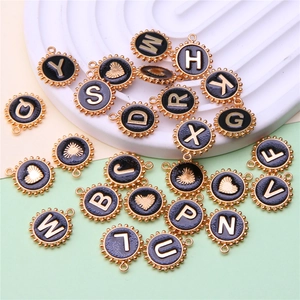 Detail of round black enamel and gold alloy letter pendants for DIY jewelry making