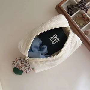 Close-up of white quilted cosmetic bag with metal zipper and soft cotton filling