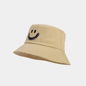 Close-up of the black smiley face print on a beige cotton bucket sun hat