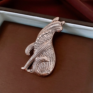 Macro view of rose gold cat brooch with geometric texture on elegant dark red silk fabric