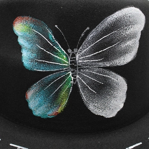 Detailed close-up of a colorful butterfly print on a black wool felt fedora hat surface
