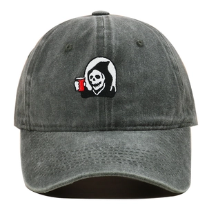 Close-up of embroidered skull reaper patch on a vintage washed grey cotton baseball cap