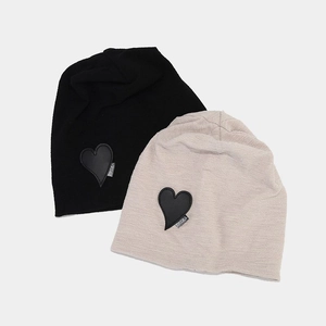 Fashionable knitted slouchy beanies in black and beige with heart patch and Drema label