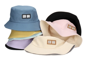Detail showing colorful bucket hats with smile logo patches in various pastel shades