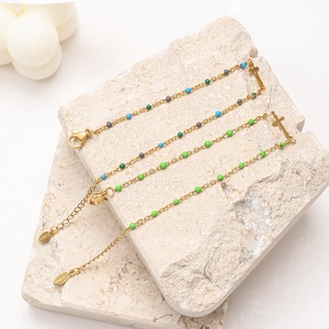 Gold stainless steel cross bracelet with colorful beads on a decorative stone base