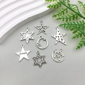Detailed view of silver star and moon charms with dream engraving on gray surface