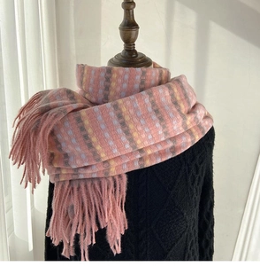 Detail of pink plaid scarf with thick tassels shown on a black knit sweater