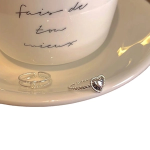 Silver stackable heart and twisted rope open rings set on minimalist white ceramic saucer