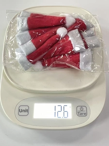 Detailed view of mini Christmas hats set on a digital scale showing a weight of 12.6g