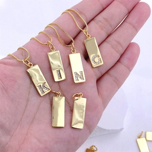 Gold rectangular pendant necklaces with zircon letters K I N G held in hand for display