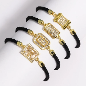 Detail of four black cord bracelets with gold pendants and sparkling cubic zirconia