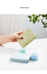 Detail of short leather wallet featuring heart embroidery and fluffy pompom zipper puller