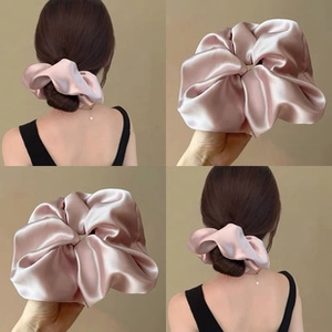 Close-up of pink silk satin scrunchie with pleated texture and soft glossy finish