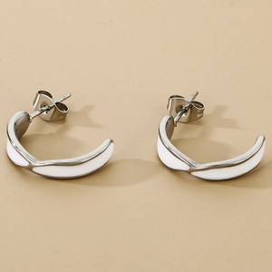 Detail of silver C-shaped stainless steel earrings with white enamel finish and butterfly backs