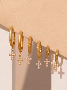 Detailed set of gold cross earrings with zirconia inlay on a beige display board