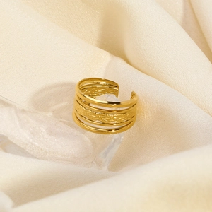 Détail de la bague dorée à couches avec motif tressé sur fond de soie blanc cassé