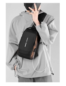 Close-up of black crossbody chest bag showing USB charging port and FASHION lettering