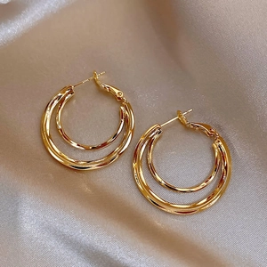 Close-up of golden hoop earrings on elegant champagne silk fabric with metallic luster