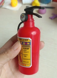 Detail of red fire extinguisher water gun toy with black handle and realistic pressure gauge