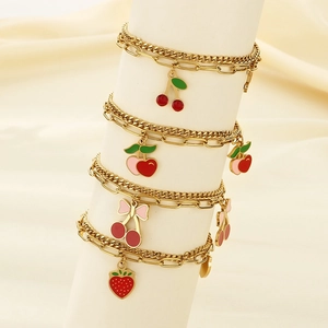 Detail of gold layered bracelets featuring strawberry and cherry enamel pendants