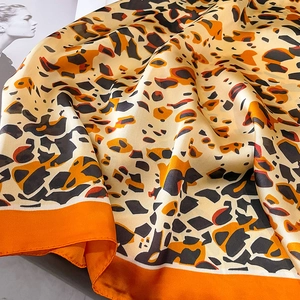 Detailed close-up of leopard print silk scarf with orange borders on magazine background