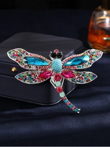 Detailed macro shot of vintage dragonfly brooch with blue crystals on dark satin