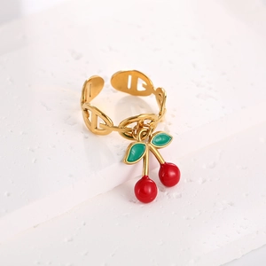 Macro detail of gold-plated stainless steel ring featuring a vibrant red cherry pendant
