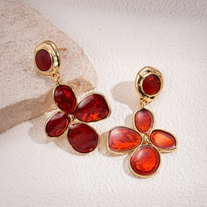 Close-up of vintage flower drop earrings with golden metal frame and red enamel filling