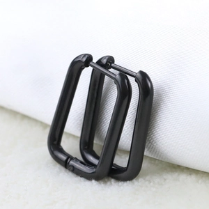 Macro shot of black polished 10mm stainless steel U-shaped huggie earrings on white fabric