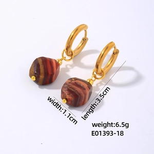 Detail view of geometric gold hoop earrings with faceted natural red stone drops