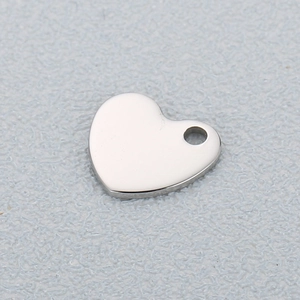 Polished silver heart pendant in stainless steel on a textured grey background