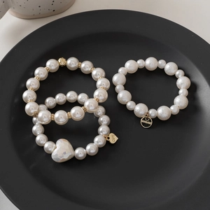 Elegant pearl hair ties with gold charms and heart pendants on a black ceramic plate