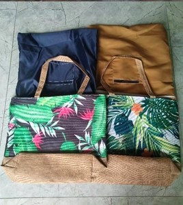 Detail view of foldable canvas tote bags in solid colors and tropical leaf patterns