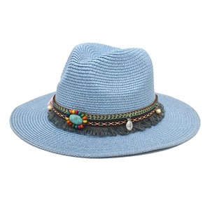 Detail of ethnic beaded band with turquoise stone and fringe on a blue straw fedora hat