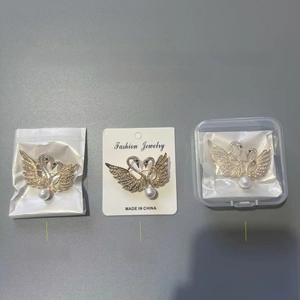 Detailed comparison of swan brooches with crystals and pearls in OPP bag and box packaging