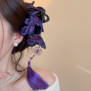 Dettaglio della pinza per capelli a farfalla ricamata viola con nappe di seta e oro