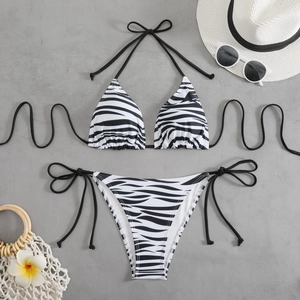 Flat lay of zebra print halter bikini set with beach accessories on grey background
