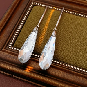 Detailed view of silver drop earrings with faceted glass crystals on green velvet
