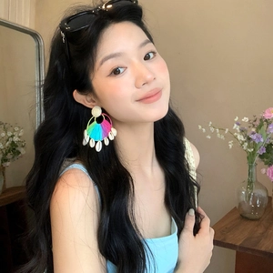 Primo piano di una modella che indossa orecchini in rafia e conchiglie colorate per l'estate