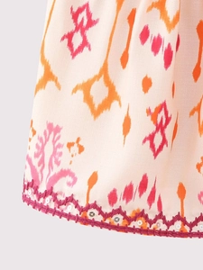 Détail macro du tissu imprimé bohème avec broderie zigzag rose et paillettes brillantes