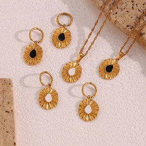 Detail view of gold wave chain necklace and earrings with sun flower texture and enamel inlay