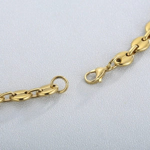 Close-up of gold coffee bean chain necklace with secure lobster clasp on grey surface