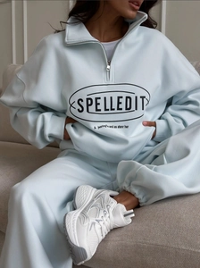 Detail of light blue half-zip sweatshirt with Spelledit branding and matching sweatpants