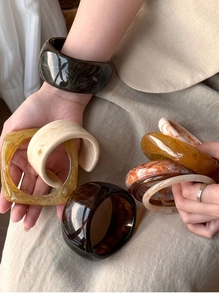 Close-up of stylish irregular resin bangles in amber, tortoiseshell, and olive green