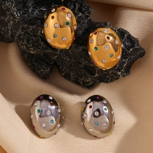 Macro shot of oval stud earrings with colorful crystals on black stone and beige silk